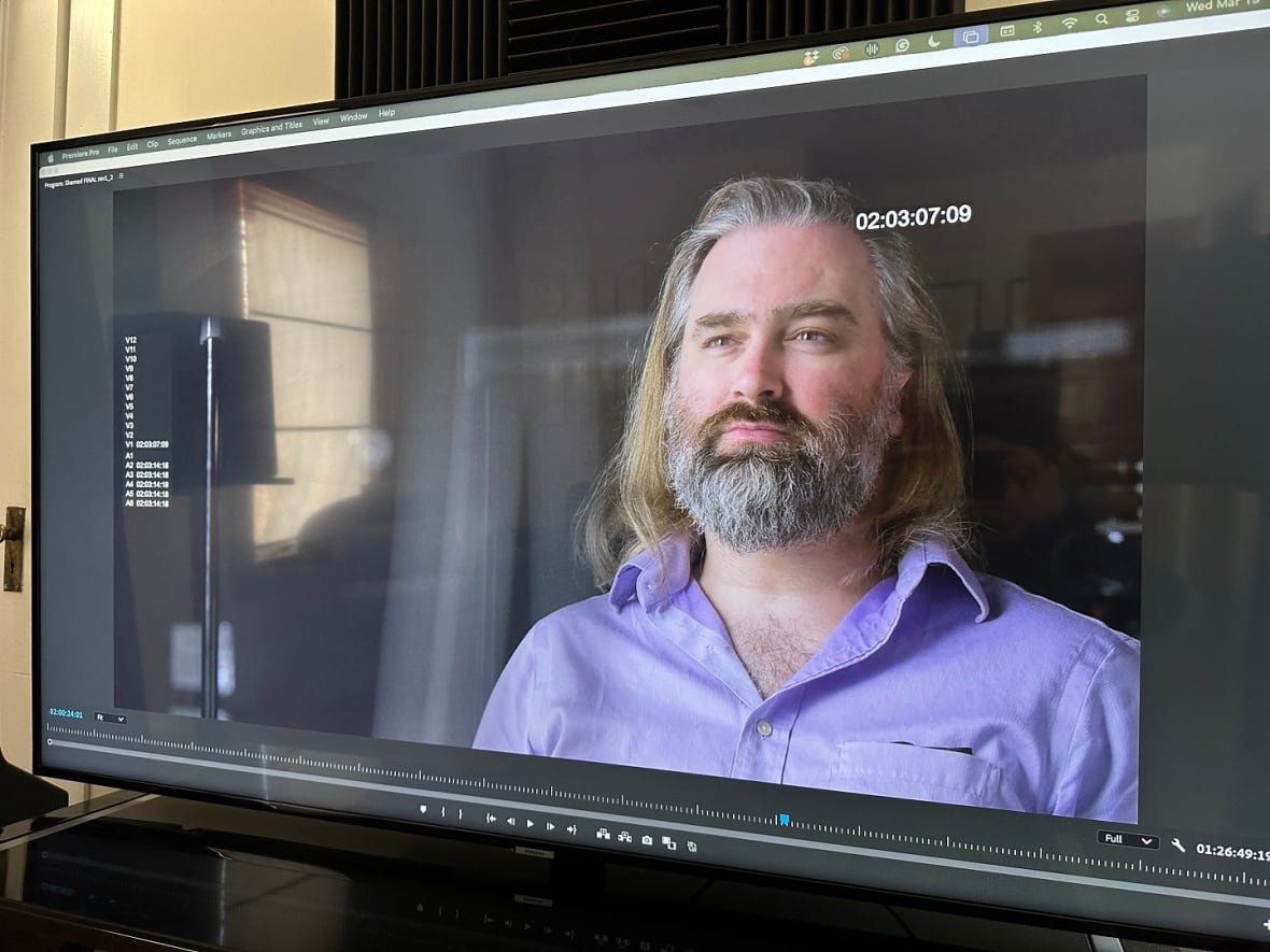 A bearded man on a television screen.
