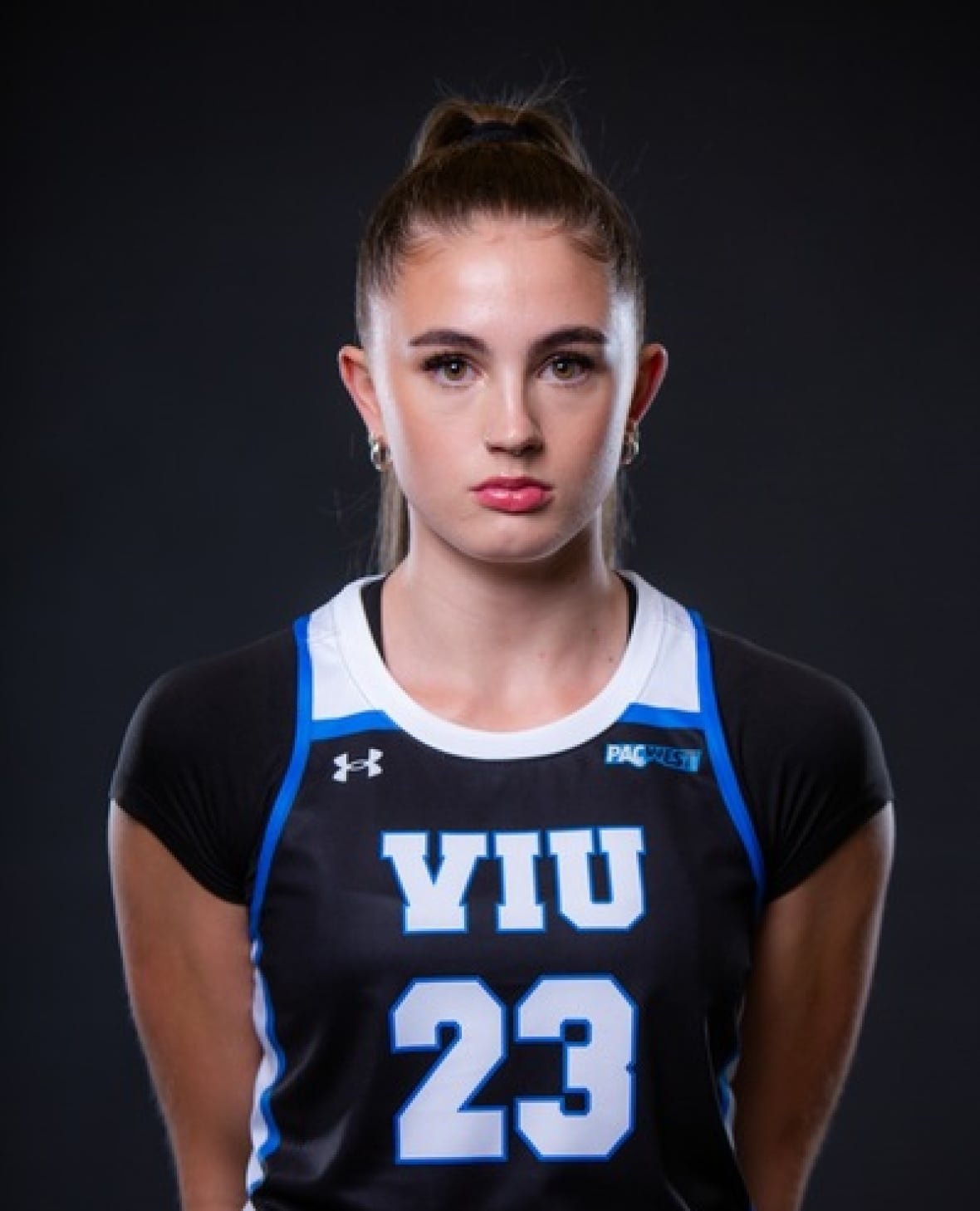 harriette-mackenzie A portrait photo of a woman in her 20s wearing a black, white and blue basketball jersey.