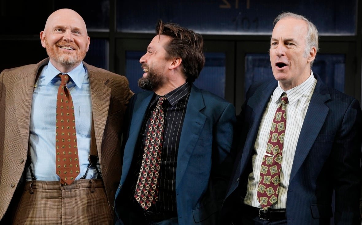 glengarry-glen-ross-broadway-opening-night Three men stand with their arms around each other, all in various stages of laughing, smiling or talking. The man in the centre is looking at the man at the far left.