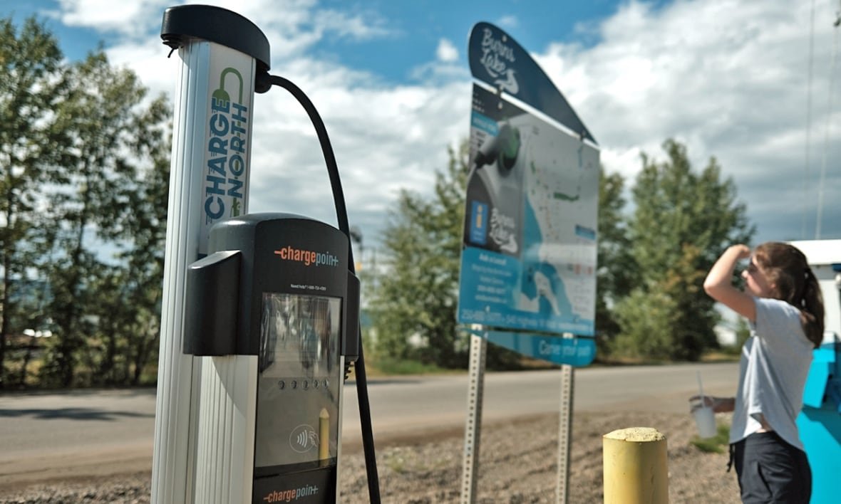 burns-lake-amenities-map A woman looks at a sign with a map beside an EV charger