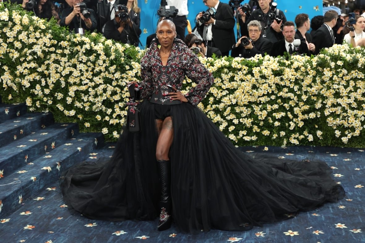 cynthia-erivo-2025-met-gala A woman wearing an embellished black corset with a tulle skirt and knee-high leather boots poses for a photo.