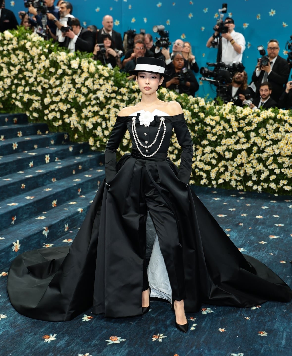jennie-2025-met-gala A woman wearing a black, long-sleeve gown with black pants and hat poses for a photo.