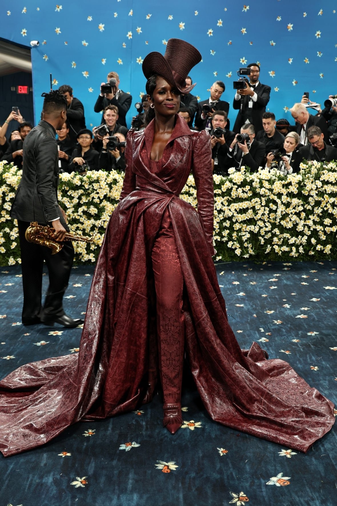 jodie-turner-smith-2025-met-gala A woman wearing a burgundy leather dress with matching pants and top hat poses for a photo.