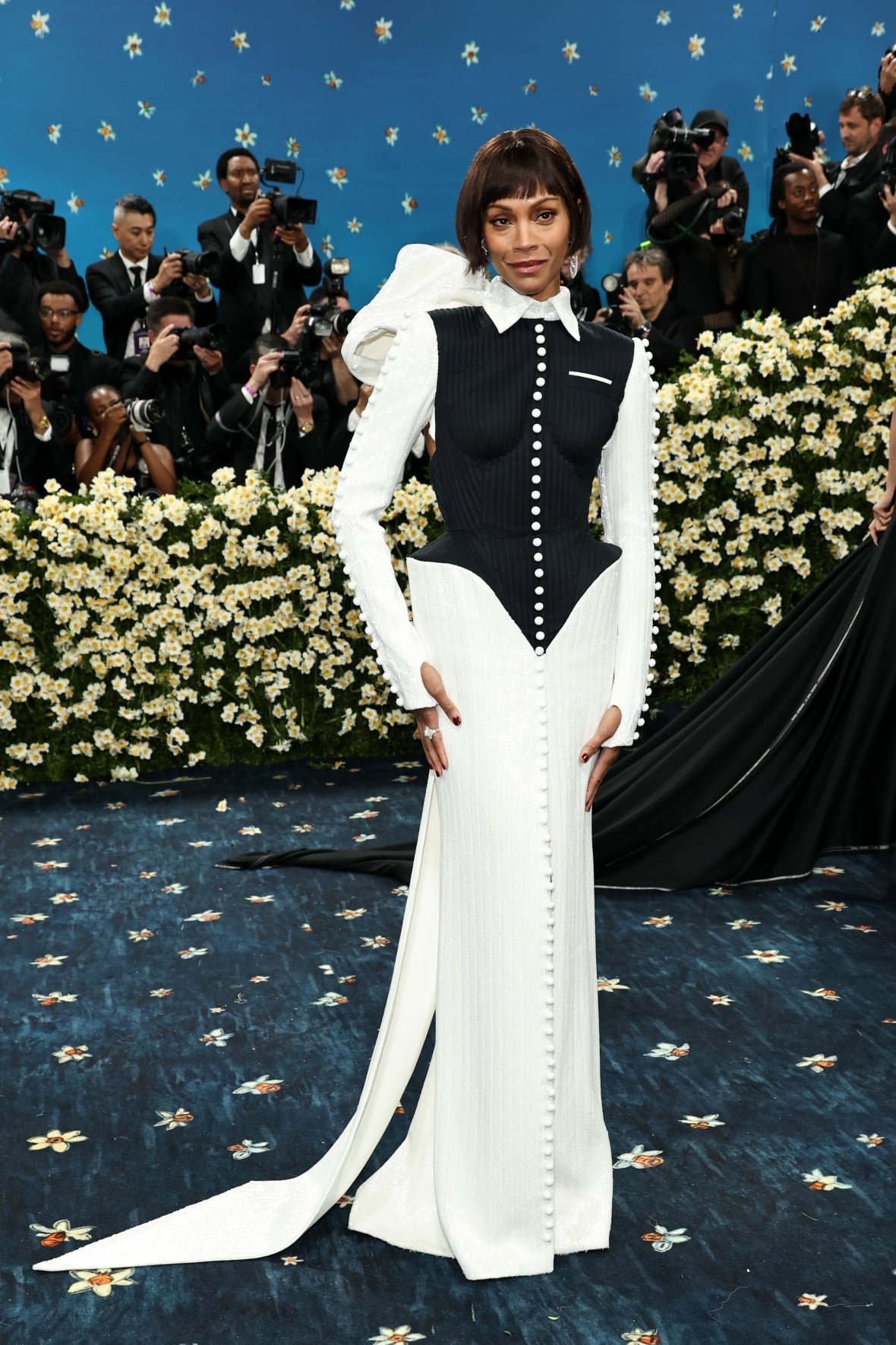 zoe-salda-a-2025-met-gala A woman wearing an elaborate white and black outfit poses for a photo.