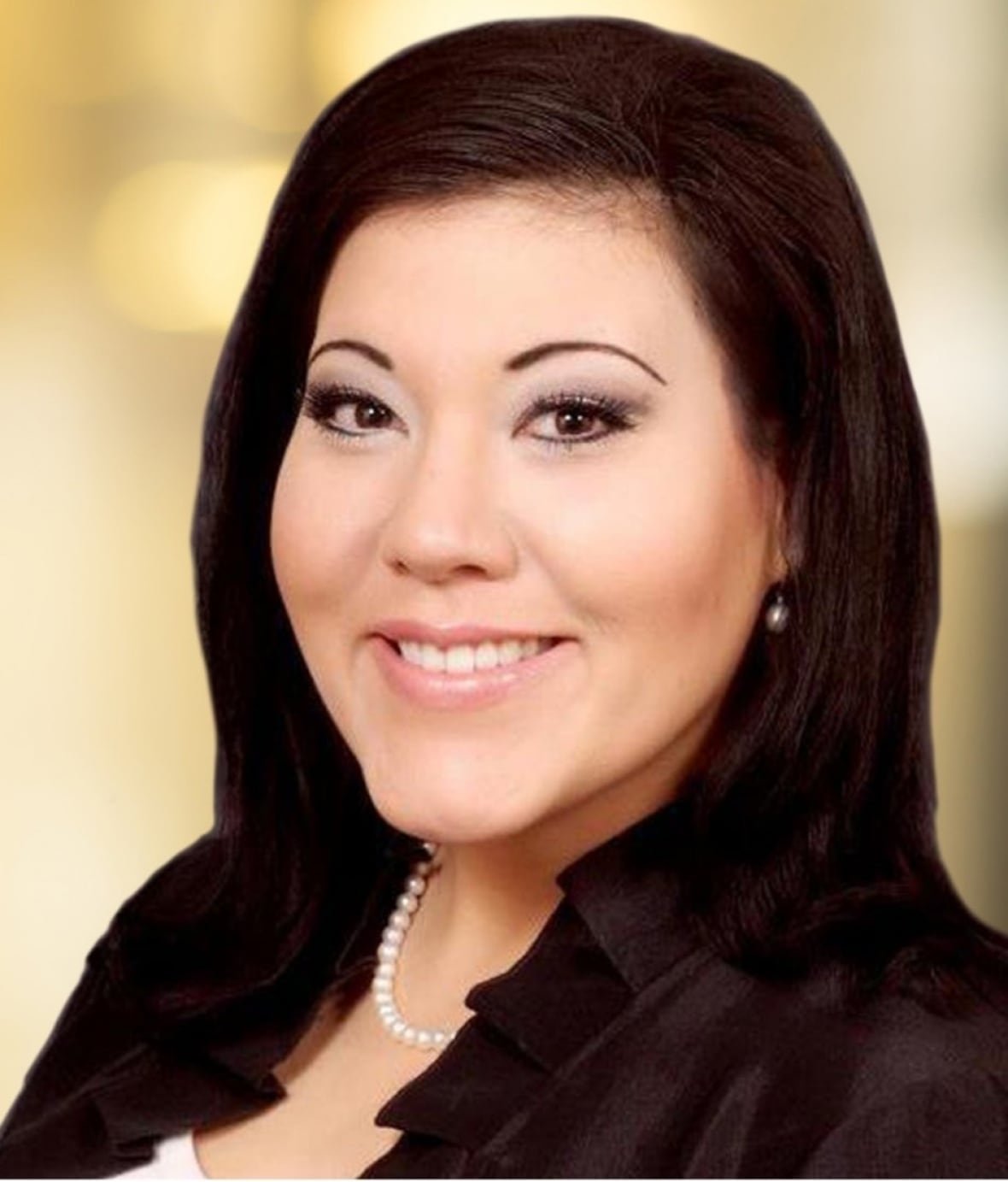 christina-cook A woman with dark hair and a pearl necklace looks at the camera and smiles.