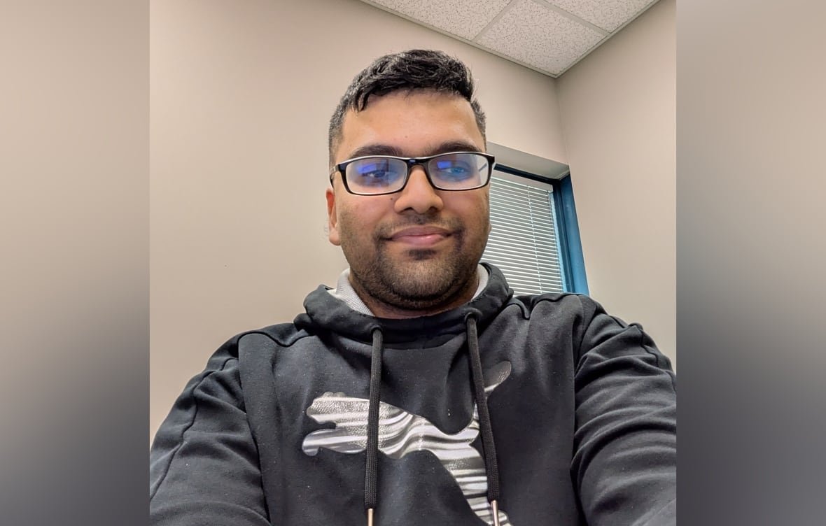 karthik-babu-menon A black-haired man wearing glasses and a dark hoodie smiles at the camera.