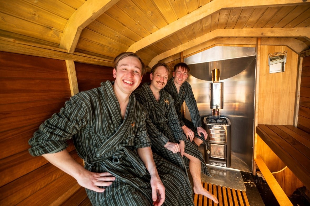 music-eurovision-sauna-fans-2 Three smiling men in robes in a sauna