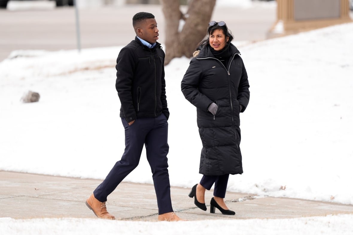 ralph-yarl-wrong-house-1 A young cleanshaven Black male is shown walking with hands in pockets outside with a woman wearing sunglasses on her head. Both are wearing coats and there's snow shown on the ground behind them.
