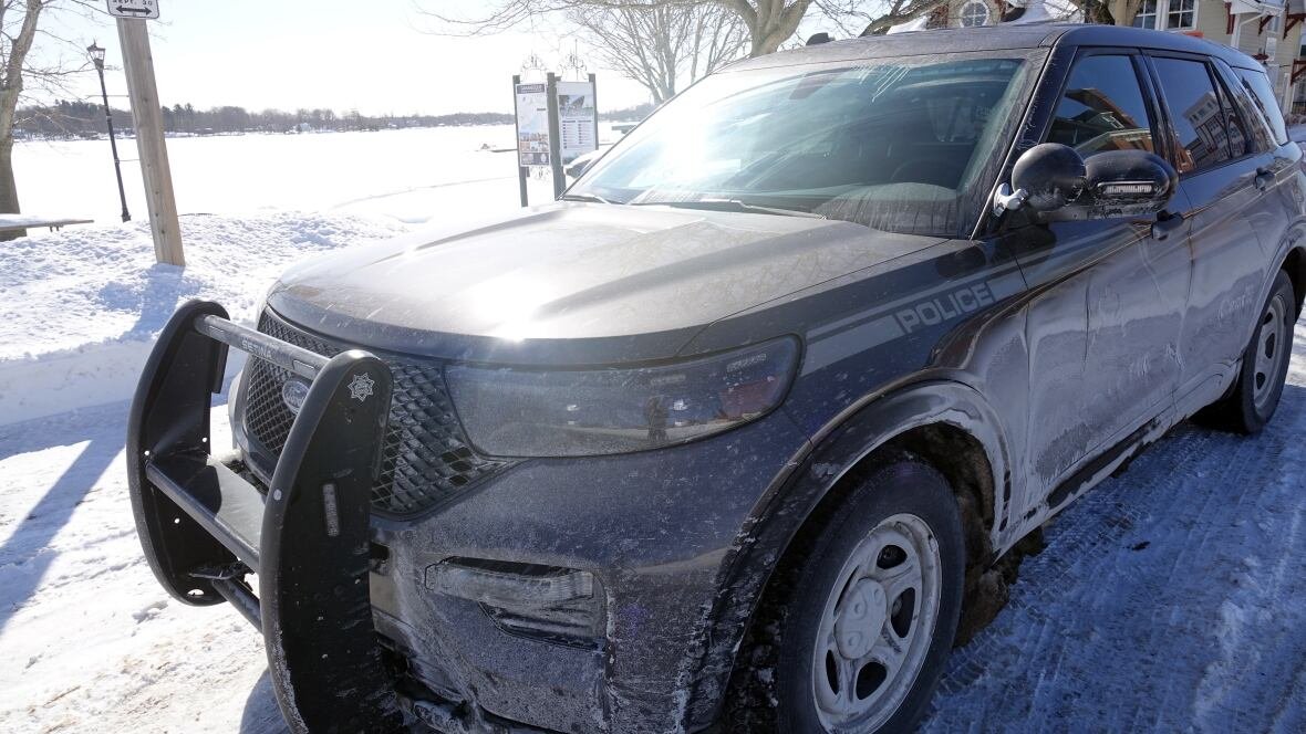 rcmp-cruiser-gananoque A black police SUV, covered in road salt and dirt, is shown near a waterfront on a bright, snowy day.