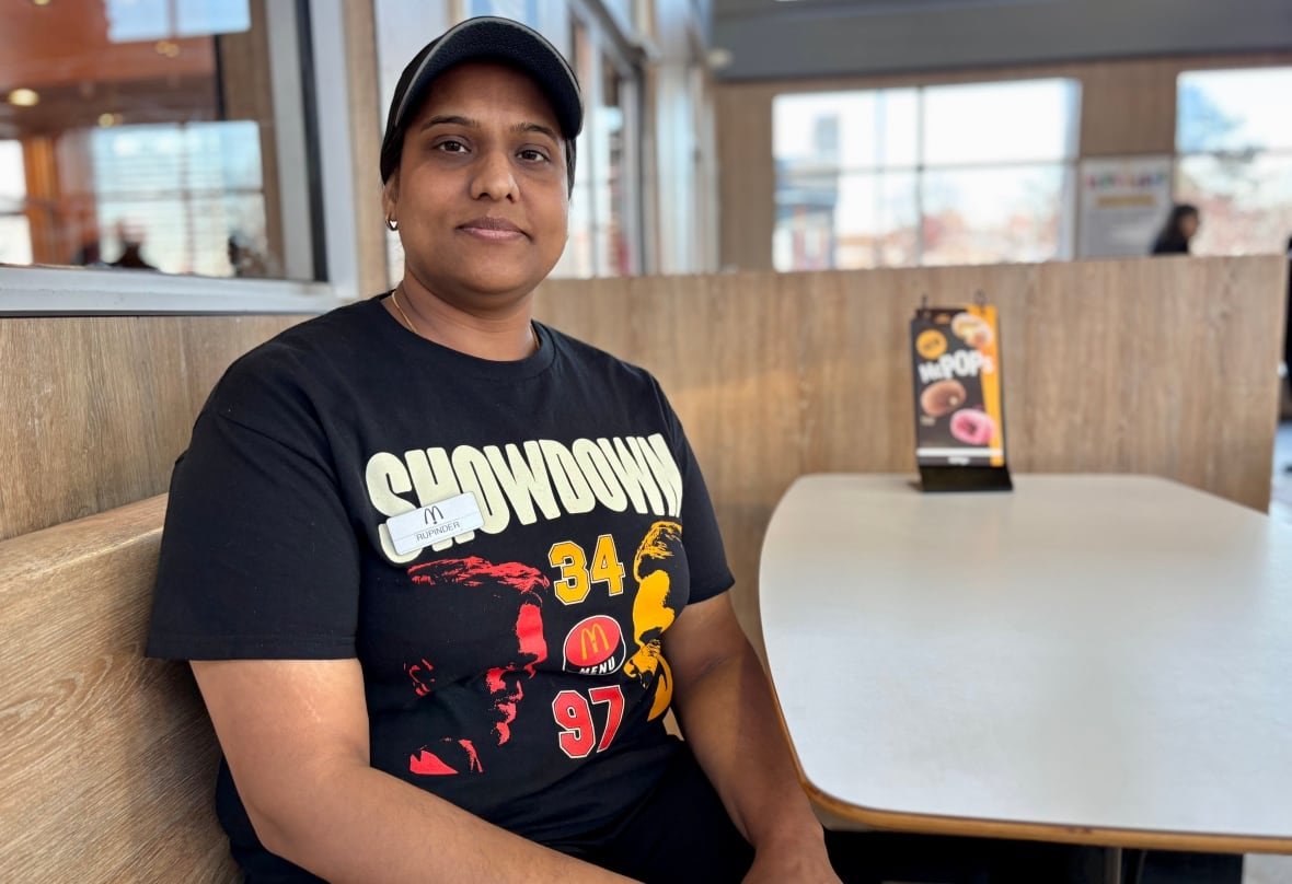 rupinder-kaur Woman in McDonald's restaurant uniform and ball cap wipes down a white table.
