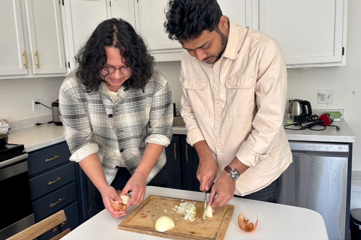 saugat-shrestha-and-sajid-oyon Two young men cut onions in a kitchen.