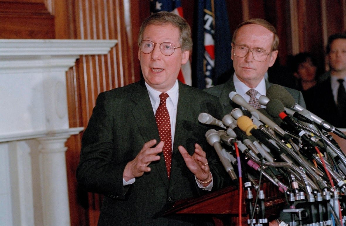 senate-ethics Two clean-shaven men wearing suit and tie stand near a bank of microphones.