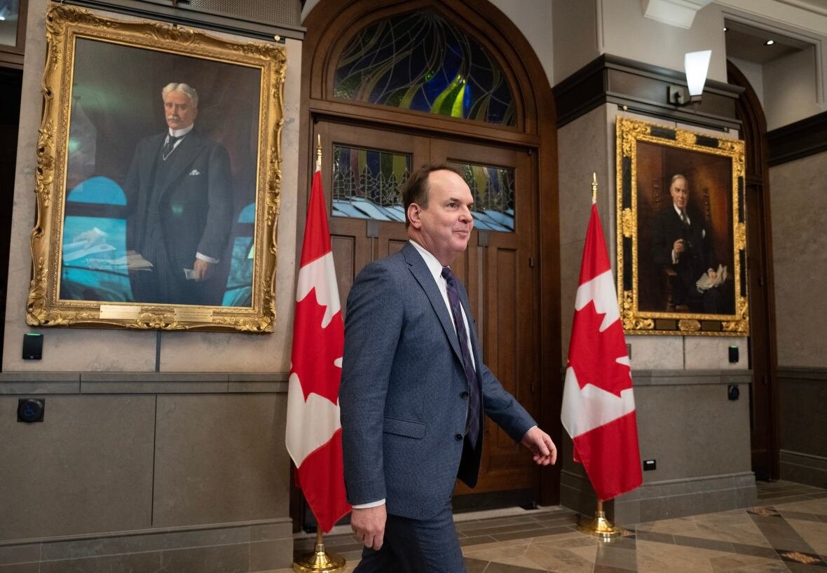 steven-mackinnon-2024 A politician walks toward a news conference in a legislature lobby.