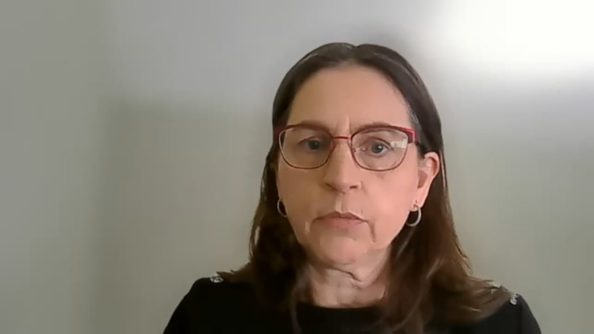 zoe-hilton A women with long brown hair wearing glasses.