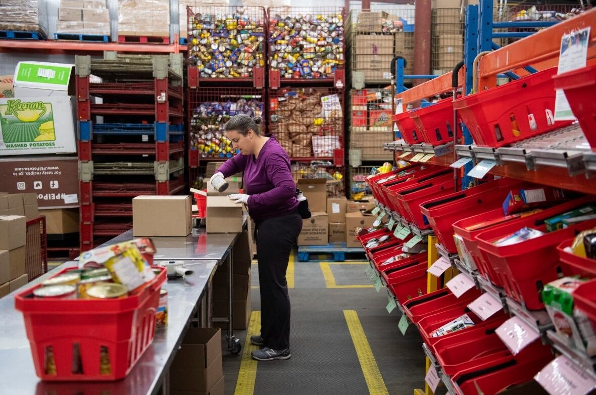 a woman sorting food at a large table in a warehouse