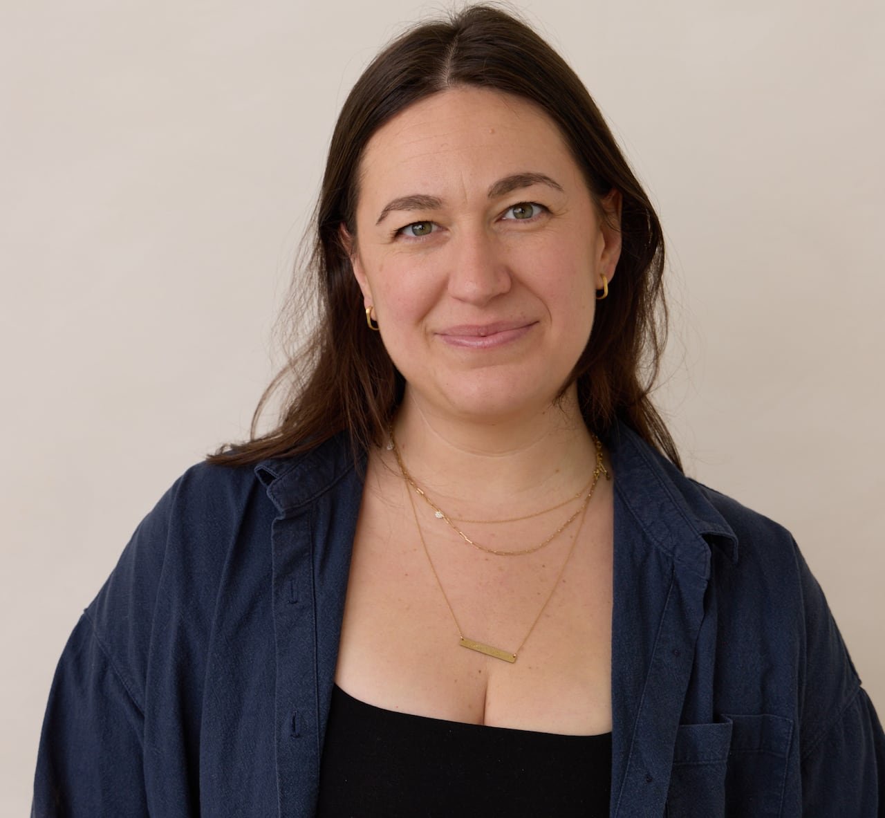 A woman wearing a black shirt and a blue overcoat is featured.