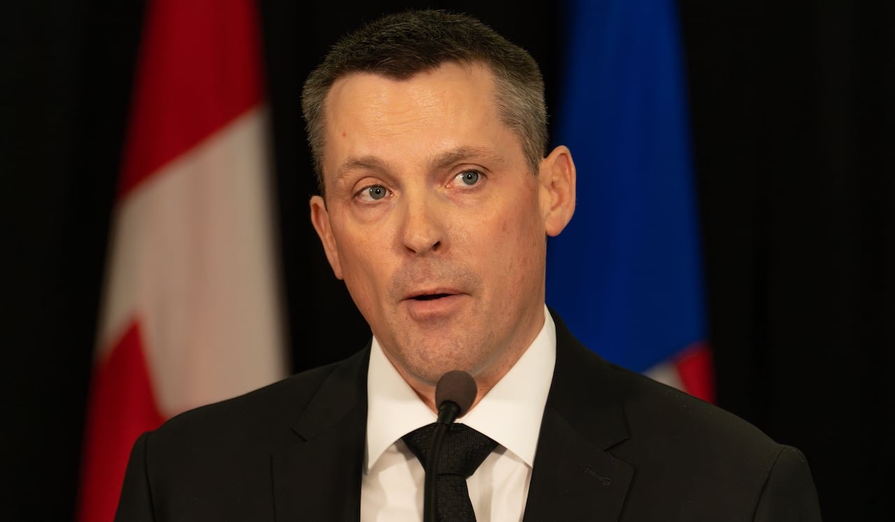 Close-up of a man standing in front of two flags.