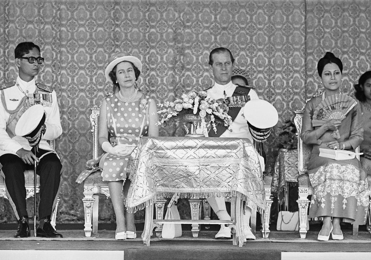 People seated on chairs in a black and white photo.