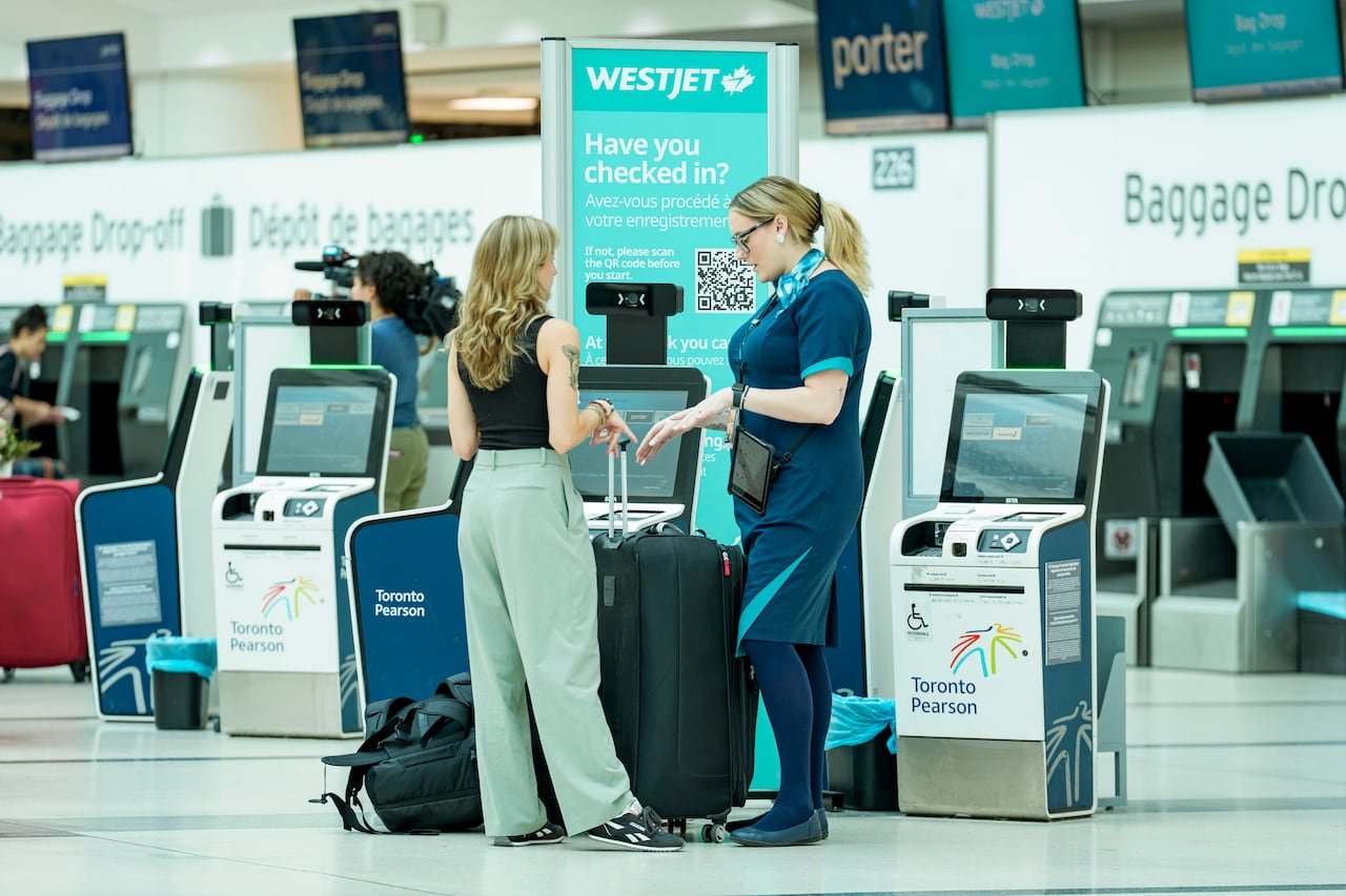 default-504 A flight attendant speaks to a customer in front of a check-in machine at an airport.