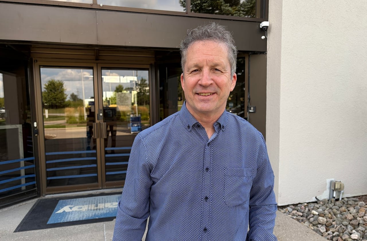 default-246 a man in a blue collared shirt stands in front of the glass doors of a building